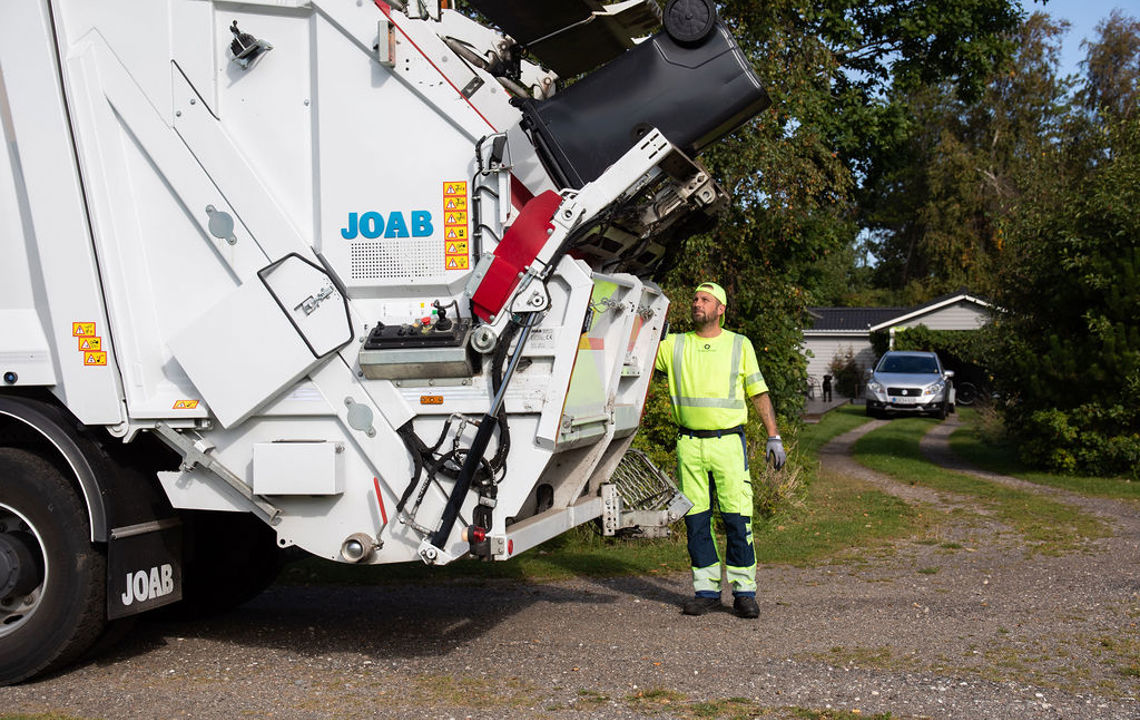 Skraldemand tømmer affaldsbeholdere i sommerhusområde Skraldemand tømmer affaldsbeholdere i sommerhusområde